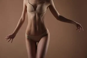 A sexy woman in a brown bikini showing off her toned abdomen after a tummy tuck abdominoplasty in Singapore.